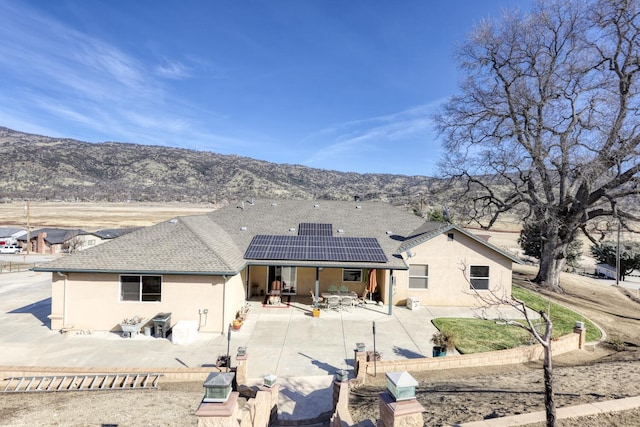 back of house with a patio, a mountain view, and solar panels