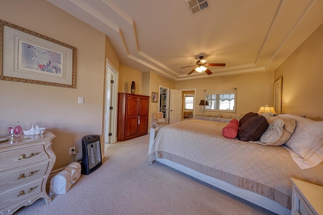 carpeted bedroom featuring ceiling fan and a tray ceiling