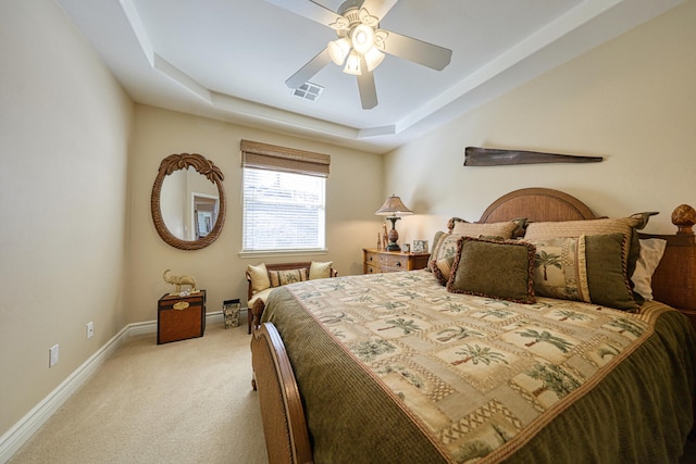 carpeted bedroom with ceiling fan and a raised ceiling