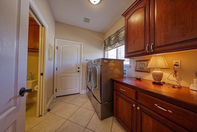 clothes washing area featuring cabinets, washing machine and dryer, and light tile patterned floors