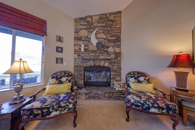 living room with lofted ceiling, a stone fireplace, and carpet flooring