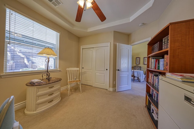 living area featuring light colored carpet, a raised ceiling, and ceiling fan