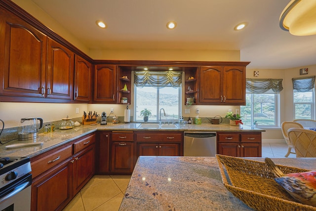 kitchen with light tile patterned flooring, sink, stainless steel appliances, light stone countertops, and a healthy amount of sunlight