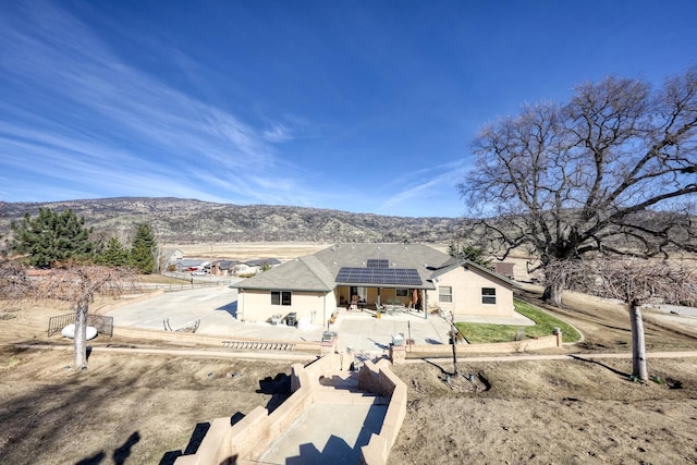 rear view of property with a mountain view, a patio area, and solar panels