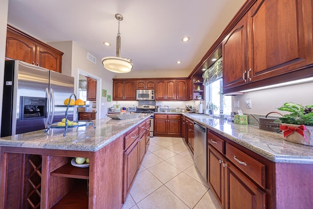 kitchen with light tile patterned flooring, decorative light fixtures, a center island, light stone counters, and stainless steel appliances