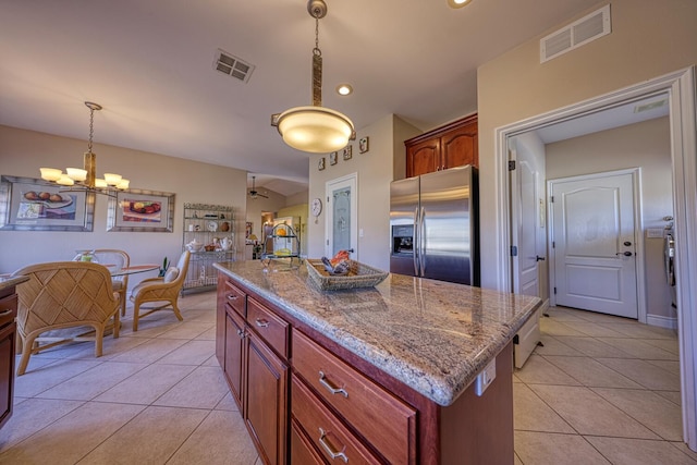 kitchen featuring stainless steel fridge, decorative light fixtures, an island with sink, and light tile patterned floors