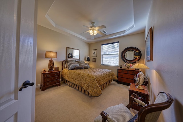 carpeted bedroom featuring ceiling fan and a raised ceiling