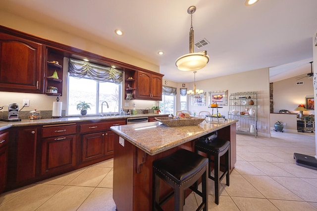 kitchen with a breakfast bar, light stone counters, decorative light fixtures, light tile patterned floors, and stainless steel dishwasher