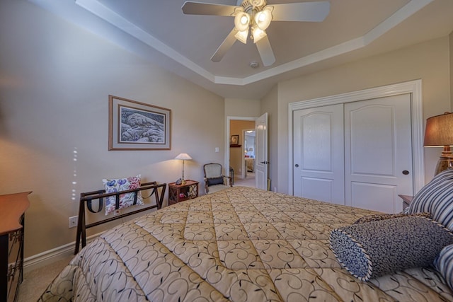 bedroom featuring ceiling fan, a raised ceiling, and a closet