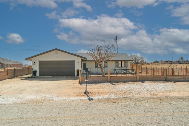 ranch-style house featuring driveway, a fenced front yard, an attached garage, and stucco siding