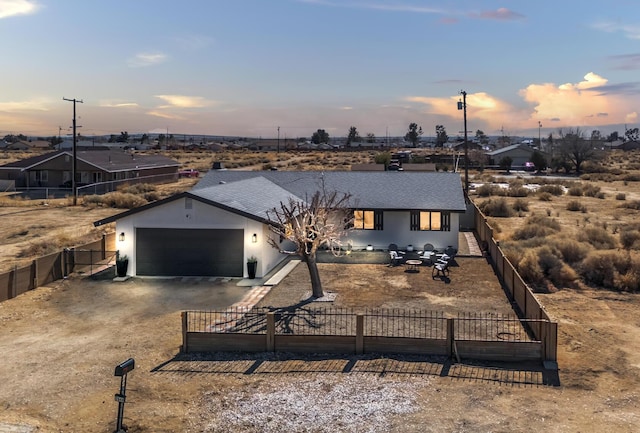 single story home featuring driveway, a shingled roof, a fenced front yard, and an attached garage