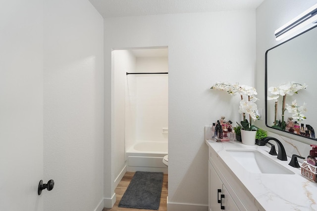 full bath with toilet, vanity, wood finished floors,  shower combination, and baseboards