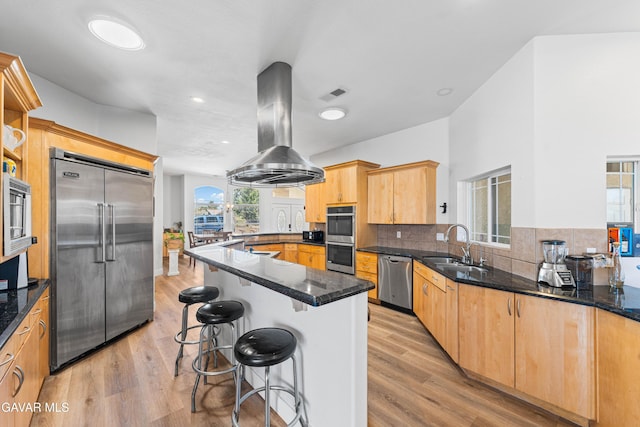 42094 W 21st St, Lancaster, CA 93536 - kitchen featuring appliances with stainless steel finishes, exhaust hood, a kitchen breakfast bar, dark stone counters, and light wood-style floors