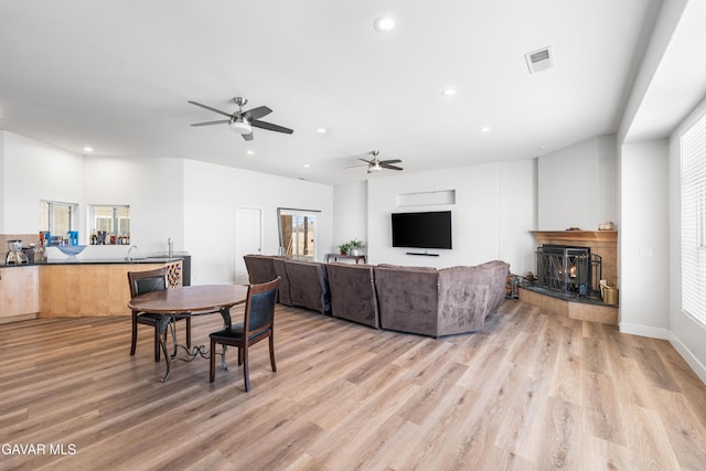 42094 W 21st St, Lancaster, CA 93536 - living room featuring recessed lighting, a lit fireplace, light wood-style floors, a ceiling fan, and healthy amount of natural light