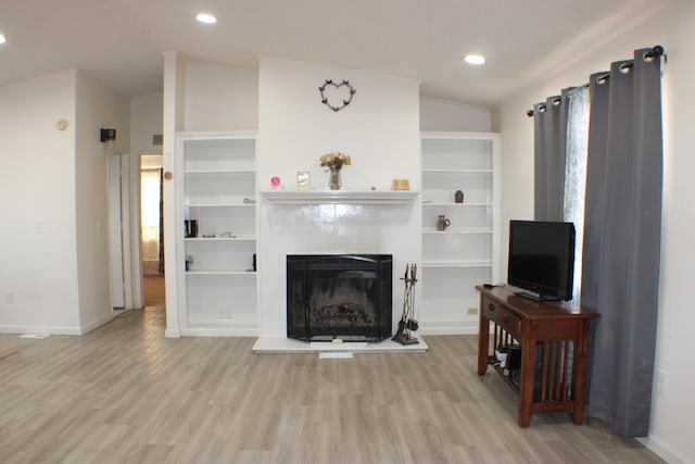 living room featuring lofted ceiling and light hardwood / wood-style floors