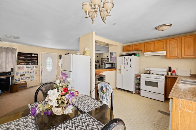 kitchen featuring a notable chandelier, white appliances, and sink