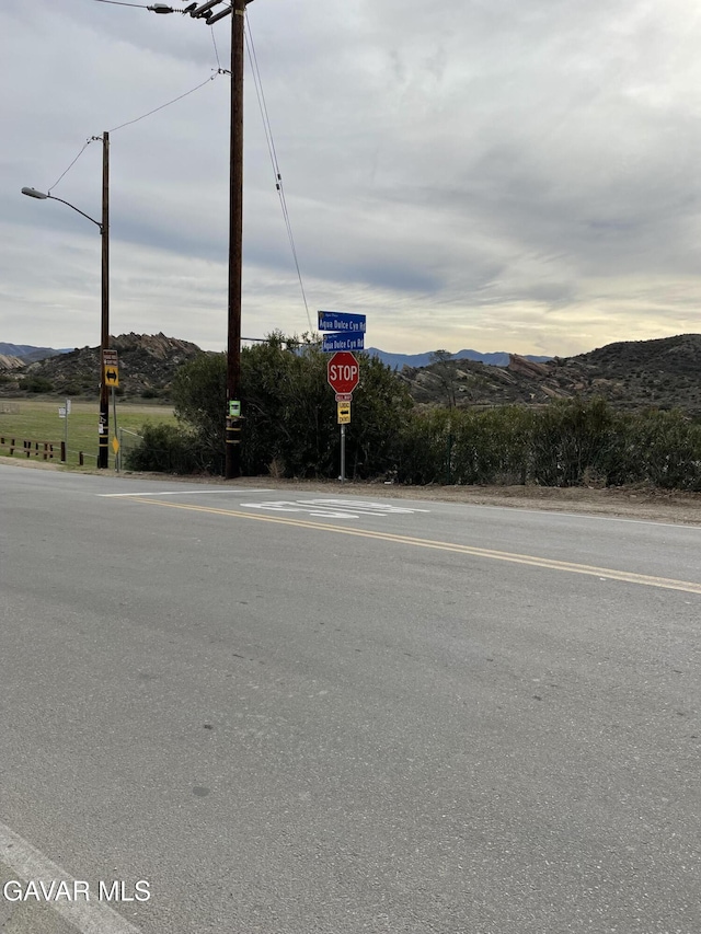 32941 Agua Dulce Canyon Rd, Agua Dulce, CA 91390 - view of asphalt road with traffic signs, a mountain view, and street lighting