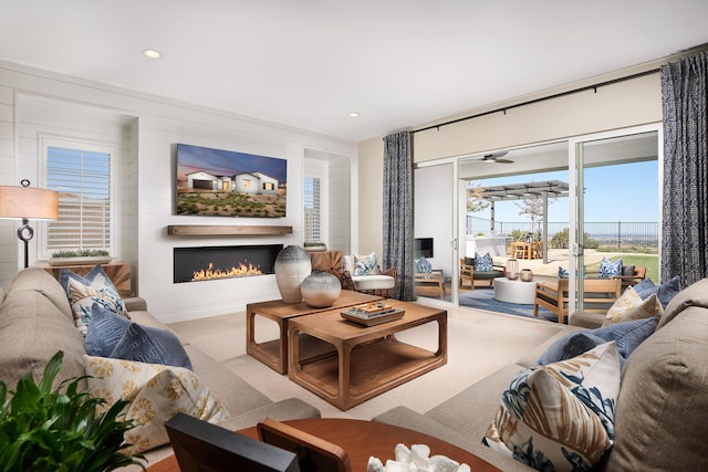 living room with a fireplace, light carpet, and ceiling fan