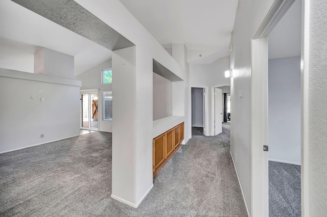 corridor featuring carpet floors and high vaulted ceiling