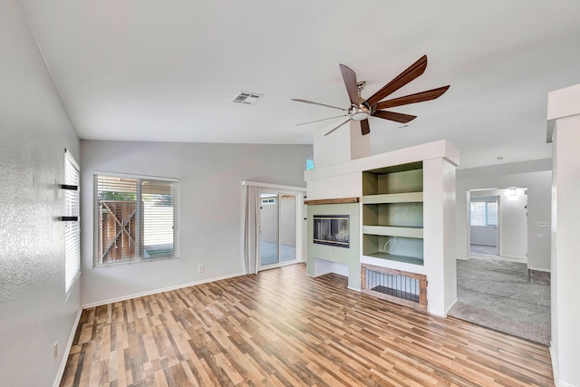 unfurnished living room featuring built in shelves, ceiling fan, light hardwood / wood-style floors, and lofted ceiling