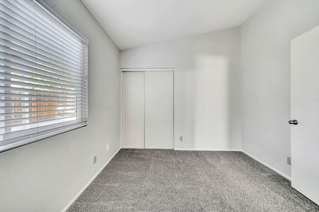 carpeted spare room with vaulted ceiling