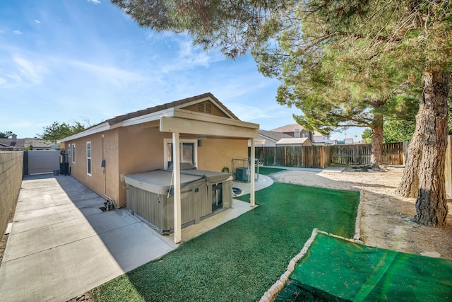 back of property featuring cooling unit, a patio area, a yard, and a hot tub