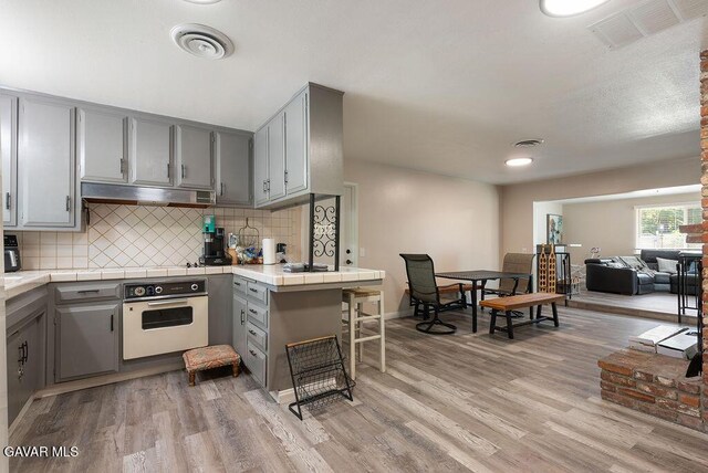 43818 Halcom Ave, Lancaster, CA 93536 - kitchen with white oven, gray cabinetry, tile counters, and recessed lighting