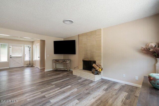 43818 Halcom Ave, Lancaster, CA 93536 - unfurnished living room featuring wood finished floors, a textured ceiling, and a brick fireplace