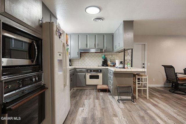 43818 Halcom Ave, Lancaster, CA 93536 - kitchen featuring white appliances, gray cabinetry, tile countertops, and under cabinet range hood