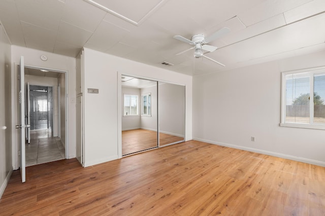 unfurnished bedroom with ceiling fan, a closet, and wood-type flooring