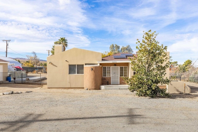 34005 Longview Rd, Pearblossom, CA 93553 - adobe home featuring stucco siding, a chimney, solar panels, and fence