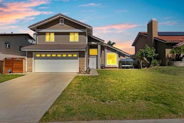 traditional-style home with a front yard, fence, driveway, an attached garage, and a tiled roof