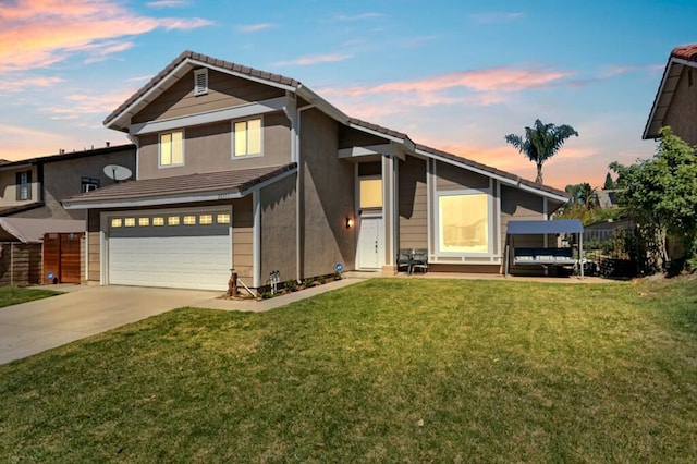 view of front of house with stucco siding, a lawn, fence, concrete driveway, and a garage