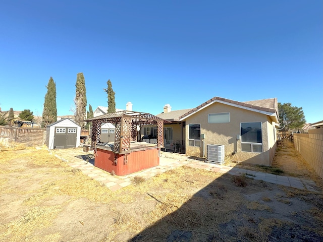 back of house featuring a gazebo, central AC, a hot tub, and a storage unit