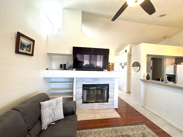 living room with ceiling fan, wood-type flooring, and a tiled fireplace