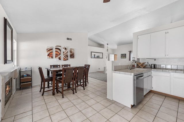 kitchen featuring visible vents, dishwasher, a premium fireplace, white cabinetry, and a sink