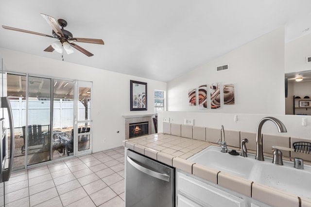 kitchen featuring a glass covered fireplace, visible vents, lofted ceiling, a sink, and dishwasher