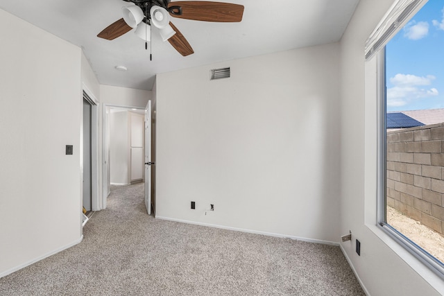 carpeted spare room with visible vents, ceiling fan, and baseboards