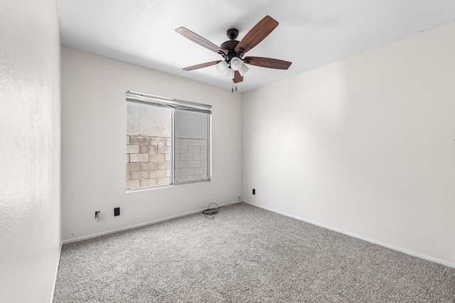 carpeted spare room with a ceiling fan and baseboards