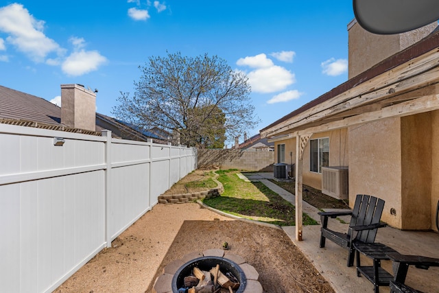 view of yard with central AC, a patio, a fire pit, and a fenced backyard