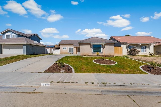 view of front of property featuring fence, driveway, stucco siding, a front lawn, and a garage