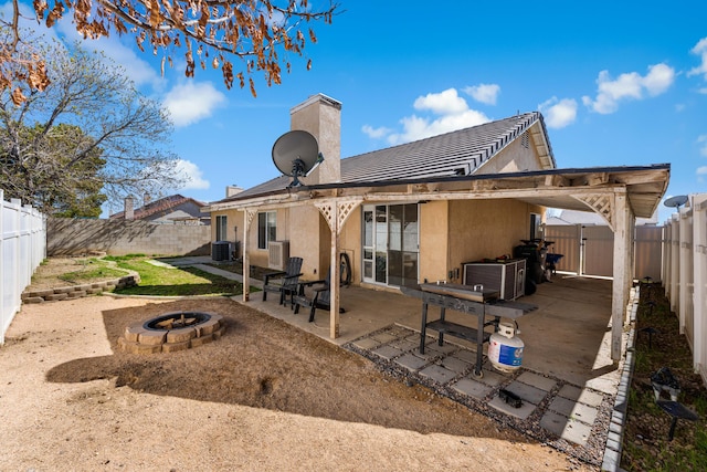 back of house with a gate, a fenced backyard, stucco siding, a fire pit, and a patio area