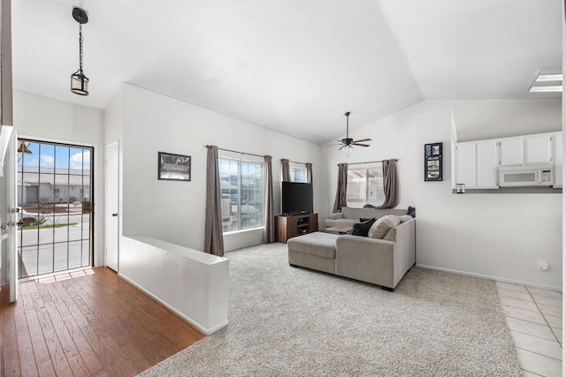 living area featuring baseboards, a ceiling fan, and vaulted ceiling