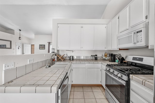 kitchen featuring tile countertops, light tile patterned floors, appliances with stainless steel finishes, white cabinets, and a sink