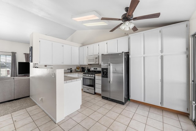 kitchen with stainless steel appliances, a peninsula, white cabinets, light tile patterned floors, and lofted ceiling