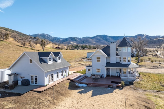 rear view of property featuring a rural view, french doors, and a deck with mountain view