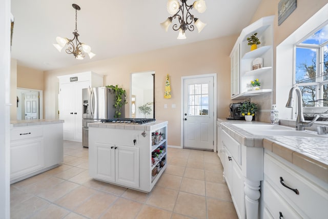 kitchen featuring appliances with stainless steel finishes, tile counters, white cabinets, and an inviting chandelier