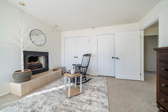 sitting room with a tile fireplace and carpet