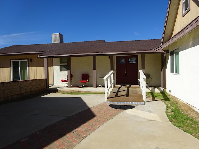 exterior space with stucco siding, a patio area, and roof with shingles