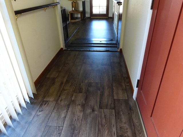 hallway featuring dark wood-type flooring, stairway, and baseboards